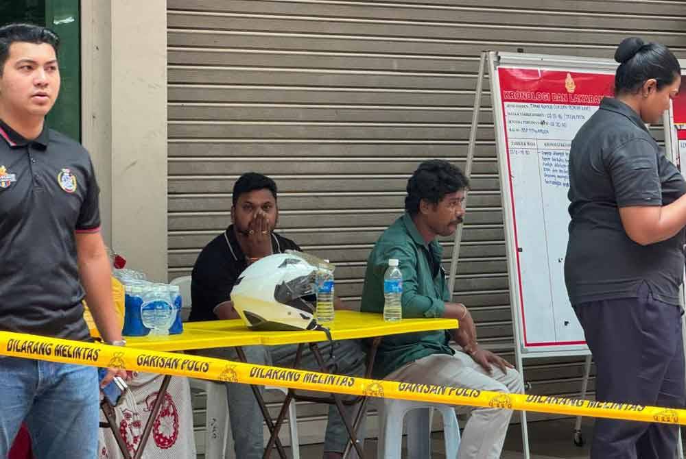 The victim's husband (seated on the right) waits for updates on the search and rescue operation for his wife in front of Masjid India on Saturday.