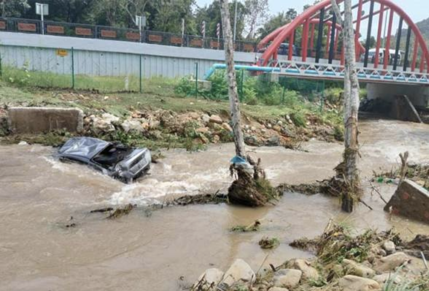 The water surge caused damage to several vehicles parked in the area, with one being swept away and later found in Sungai Perangin, police said. - Photo: PDRM