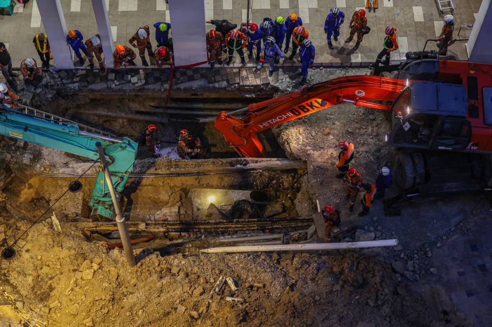Fire and Rescue Department personnel actively working to rescue a tourist who fell into a sinkhole that opened up at her feet in Jalan Masjid India, yesterday. - Photo by Bernama