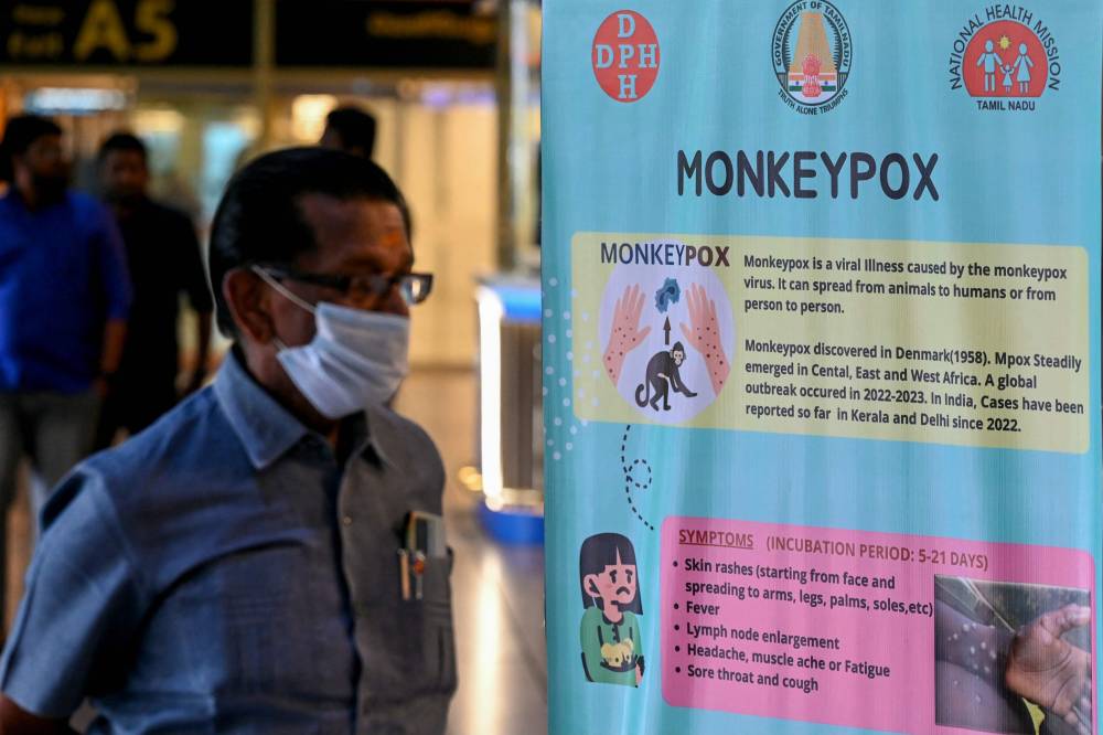 Passengers walk past the mpox awareness banner at Anna International Airport terminal in Chennai on August 21, 2024. (Photo by AFP)