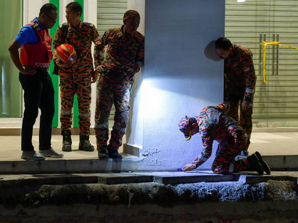 Kuala Lumpur Fire and Rescue Department (JBPM) Deputy Director Rozihan Anwar Mamat (left) inspects the sinkhole at Masjid India yesterday. - Photo by Bernama