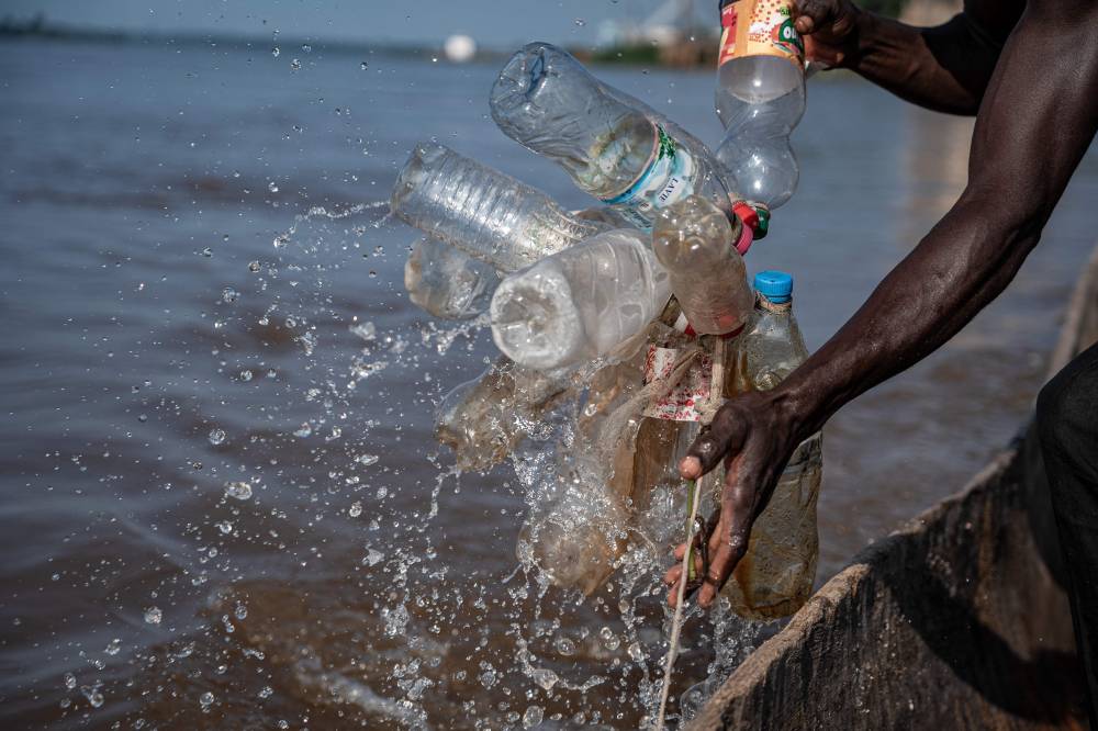 A sandfisher hooks his canoe to a makeshift anchor to avoid being swept away by strong currents on the banks of the Ubangui River at the outskirts of Bangui on August 16, 2024. - Photo by AFP