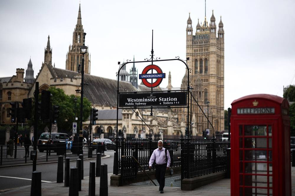 Pedestrian walks out of the Westminster tube station with the Palace of Westminster, home to the Houses of Parliament, in the background, in central London, on September 2, 2024. - Photo by AFP
