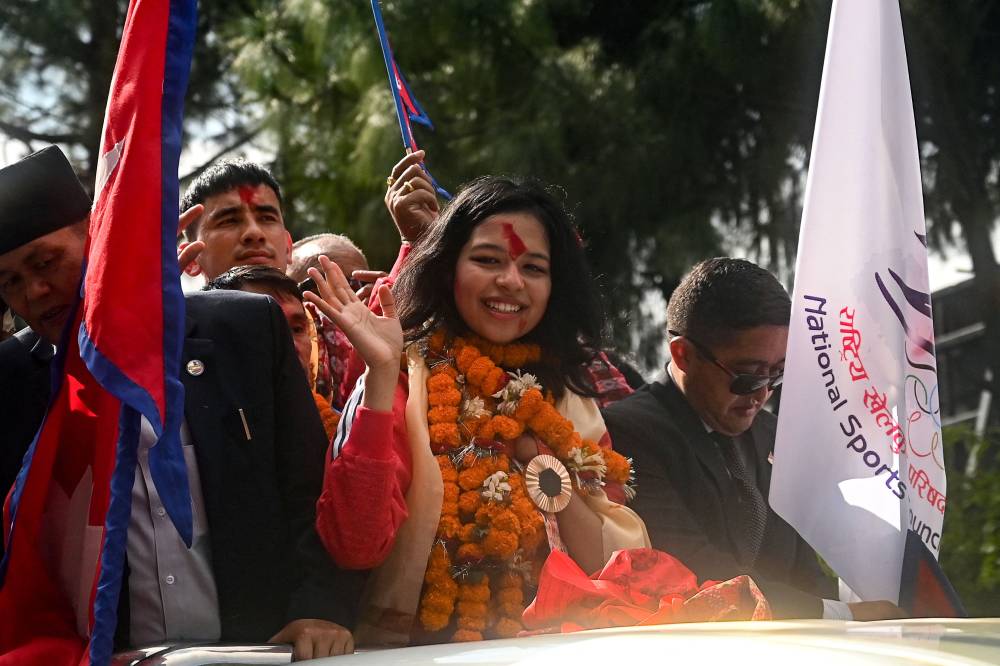 Paris 2024 Paralympic Games taekwondo bronze medallist Palesha Goverdhan (C) waves to the crowd with her medal upon her arrival at Tribhuvan International Airport in Kathmandu on September 4, 2024. - Photo by AFP