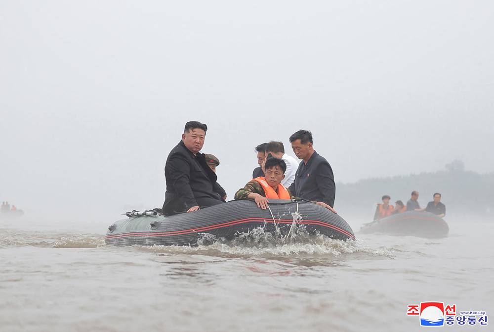 This recent undated photo released by North Korea's official Korean Central News Agency (KCNA) shows North Korea's leader Kim Jong Un (left) riding in a dingey through flood waters as he inspects the area for damage after record-breaking heavy rains on July 29 in the city of Sinuiju in North Pyongan Province. Photo by KCNA VIA KNS/AFP