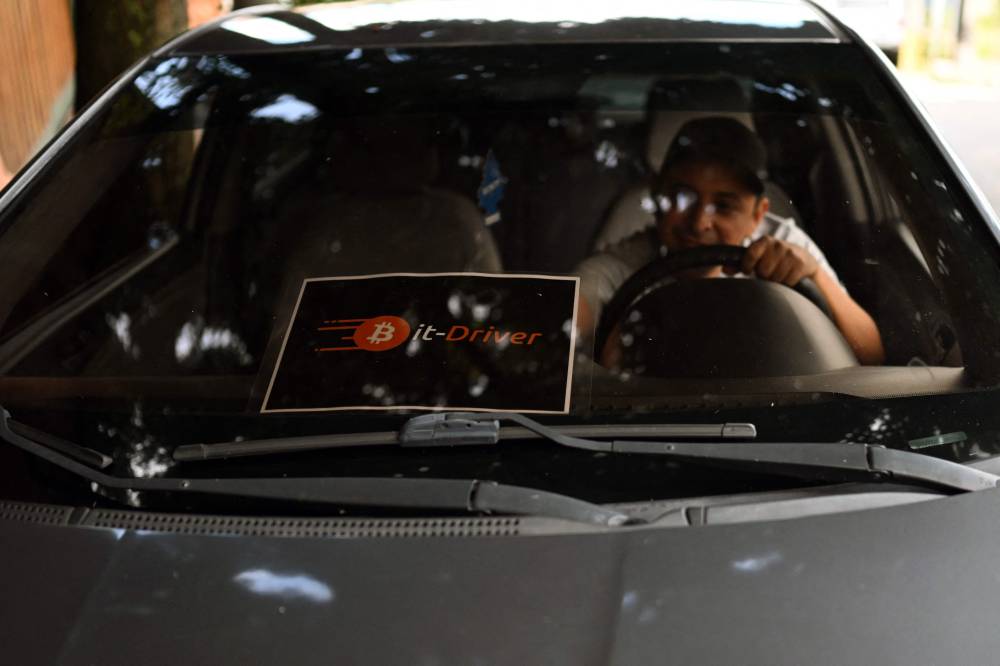 Taxi driver Napoleon Osorio places a sign on his car to let customers know that he accepts payments in bitcoins in San Salvador on September 4, 2024. - Photo by AFP