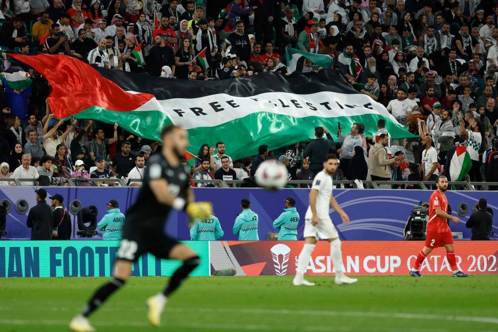 Football supporters unfurl a giant Palestinian flag emblazoned with the slogan "Free Palestine" in the stands during the Qatar 2023 AFC Asian Cup Group C football match between Iran and Palestine at the Education City Stadium in Al-Rayyan, west of Doha on January 14, 2024. - Photo by AFP