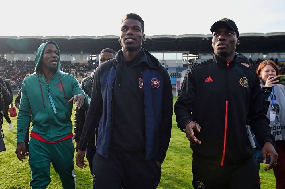 (FILES) In this photograph taken on December 29, 2019 France national team player Paul Pogba (C) and his brothers Mathias Pogba (R) and Florentin Pogba walk on the pitch prior to a football match between All Star France and Guinea at the Vallee du Cher Stadium in Tours, central France, as part of the "48h for Guinea" charity event. - Photo by AFP