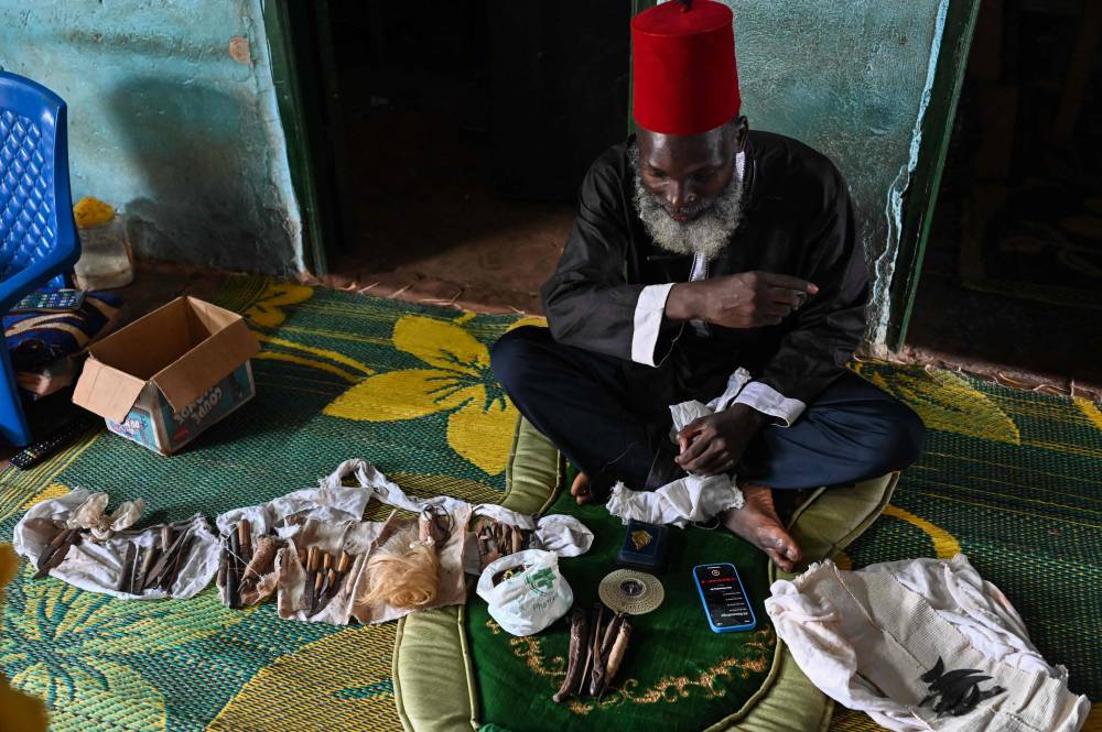 Mory Bamba, a Muslim religious leader who fights against the excision of girls, looks at excision instruments abandoned by former circumcisers in his village near Touba on July 10, 2024. - Photo by AFP