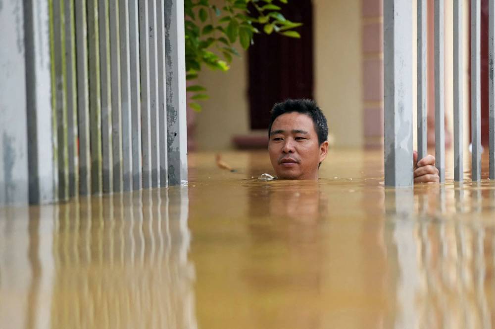 A man wades through flood waters outside his house in Thai Nguyen province on September 10, 2024, in the aftermath of Typhoon Yagi hitting northern Vietnam. Tens of thousands of people were forced to flee their homes on September 10 as massive floods inundated northern Vietnam in the wake of Typhoon Yagi, and the death toll climbed to 82. (Photo by Huu Hao / AFP)