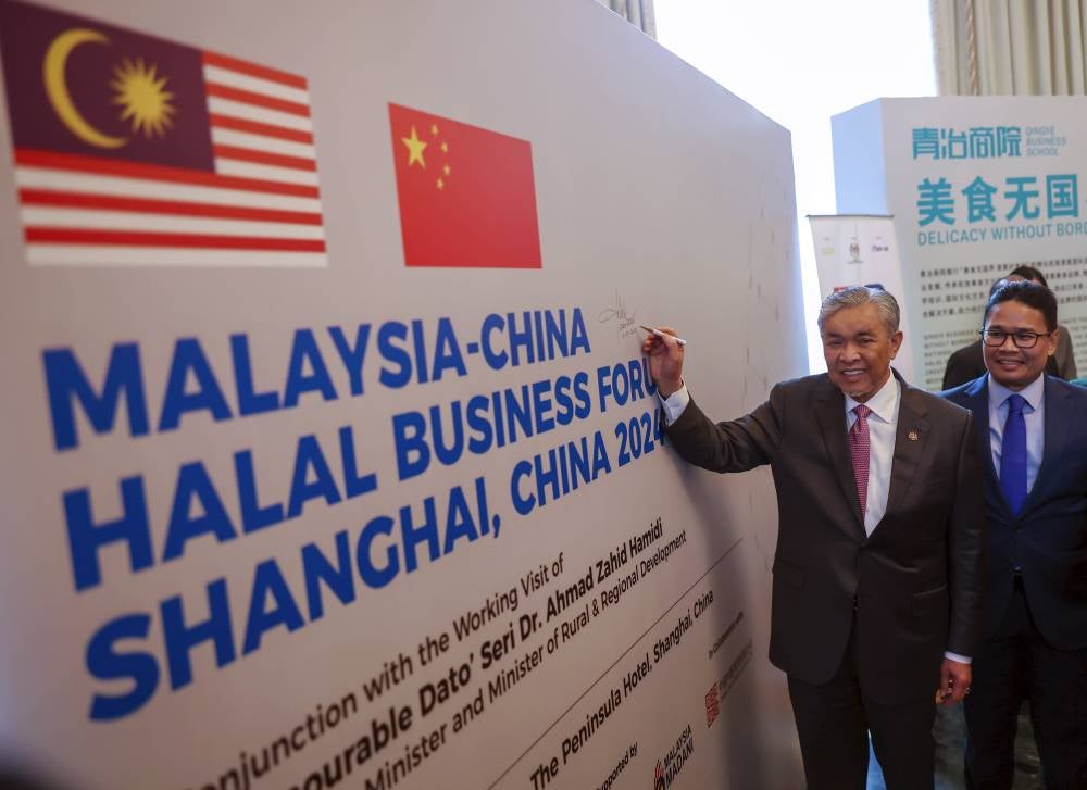 Deputy Prime Minister Datuk Seri Ahmad Zahid Hamidi (left) signs a poster for the Malaysia-China Halal Business Forum after the conclusion of the roundtable session of the forum in Shanghai, China on Sept 10, 2024. - Photo by Bernama