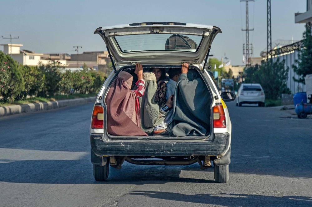 Afghan burqa-clad women travel on the back of a local taxi in Kandahar on September 9, 2024. (Photo by AFP)