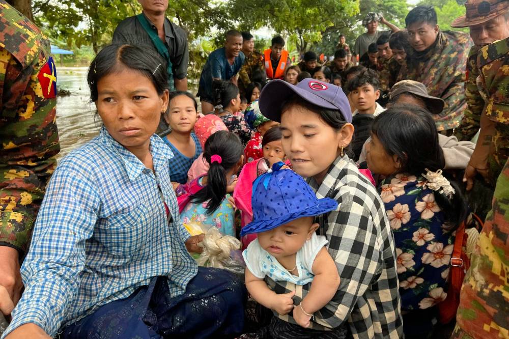 Residents are helped through flood waters by military personnel in Pyinmana in Myanmar's Naypyidaw region on Sept 13, 2024, following heavy rains in the aftermath of Typhoon Yagi. - (Photo by SAI AUNG MAIN / AFP)