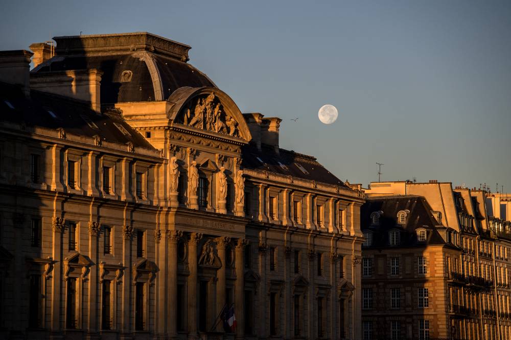 The full moon is pictured over The Cour de Cassation of Paris on Sept 26, 2018. - (Photo by Christophe ARCHAMBAULT / AFP)