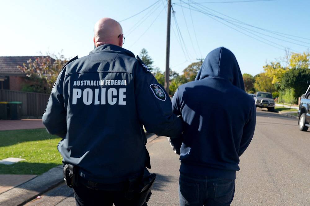 An Australian Federal Police officer arresting a suspect allegedly involved in an encrypted messaging app used by criminals worldwide to facilitate drug deals and order killings, at an unknown location. Photo by Handout / Australian Federal Police/AFP