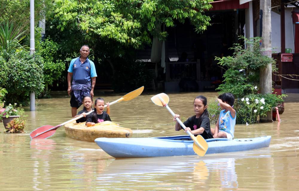 Three siblings, Syalia Izz Zara, 12, Syasya Auni Amani, 10, and Syafia Afrin Nafeesa, 7, enjoy kayaking in the flooded yard of their relative's home in Kampung Titi Gajah, Alor Setar today. (BERNAMA PHOTO)
