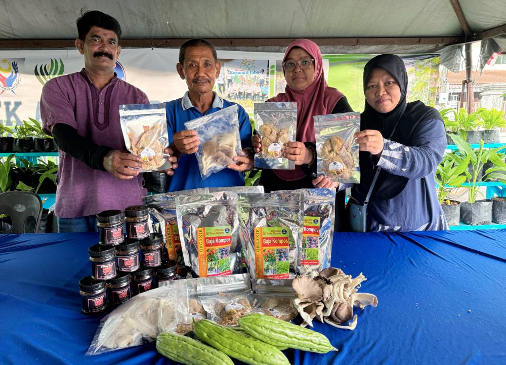 Zainal Abidin Ariffin (second from left) with the KRT community showcasing the yields obtained through urban farming, such as pekasam tilapia fish, mushrooms and bitter gourd, which have now become an additional source of income for them. Photo by Bernama.