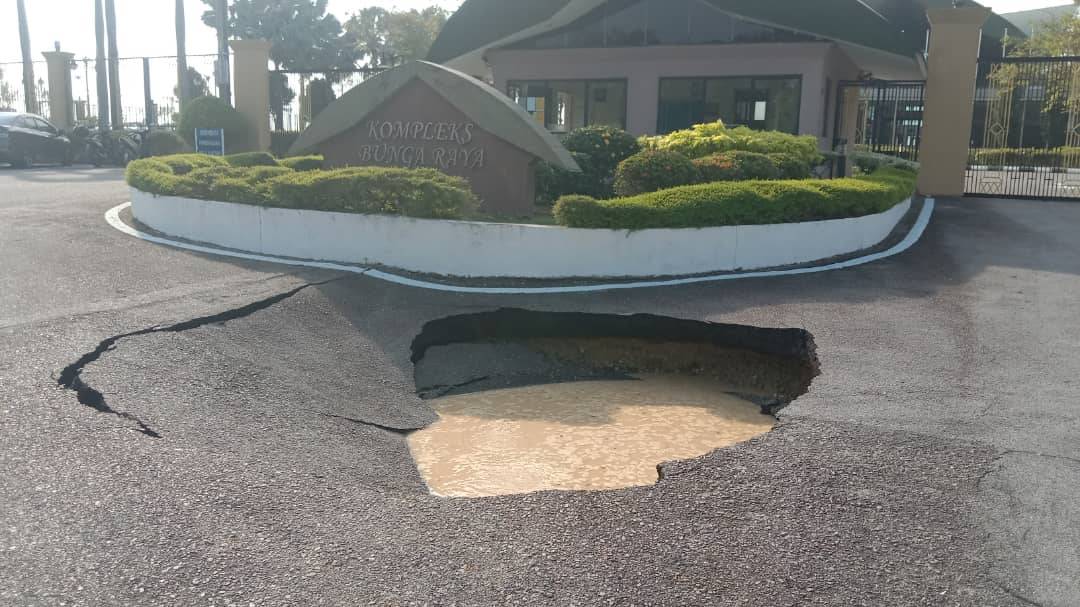 A one-metre deep sinkhole at the entrance to the Bunga Raya Complex, KLIA, is suspected to have been caused by a sewage pipe leak. - Photo: Works Ministry Facebook