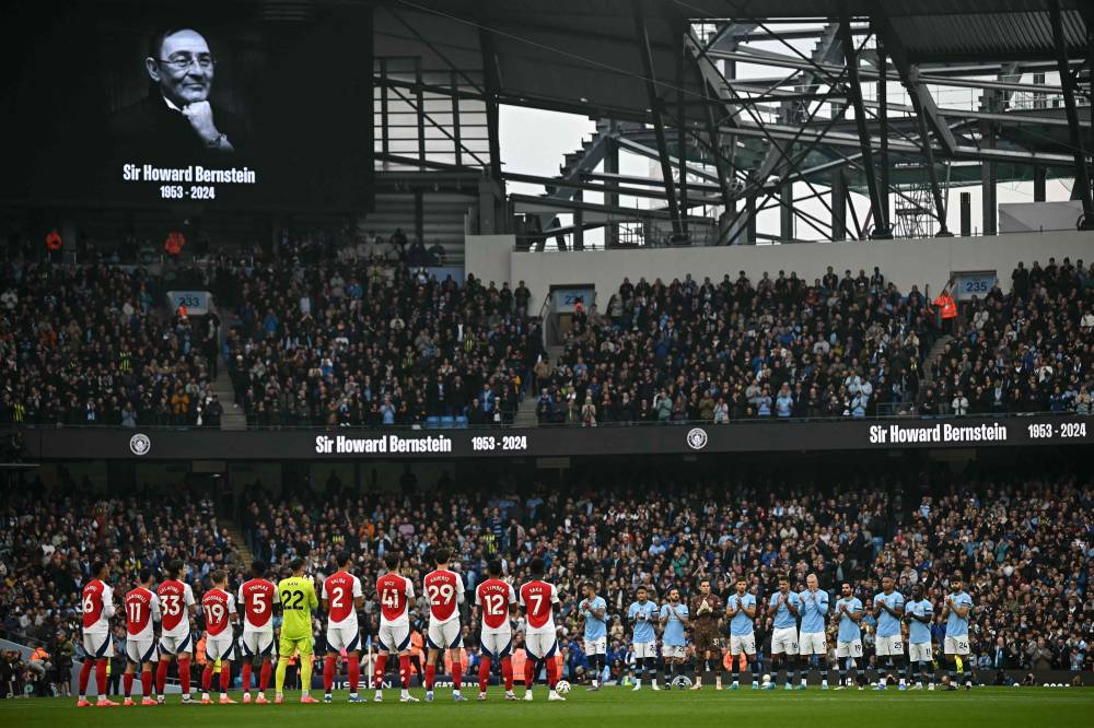 Players take part in a moments applause in memory of previous Chief Executive of Manchester City council Howard Bernstein during the English Premier League football match between Manchester City and Arsenal at the Etihad Stadium in Manchester, north west England, on September 22, 2024. (Photo by AFP)