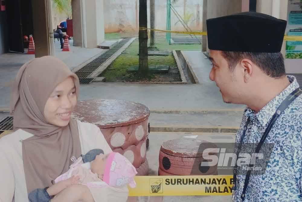 Barisan Nasional's Mahkota candidate Syed Hussien (right) checks on Nur Syafiqah, who arrived at the polling centre with her 30-day-old baby. - Photo by Sinar