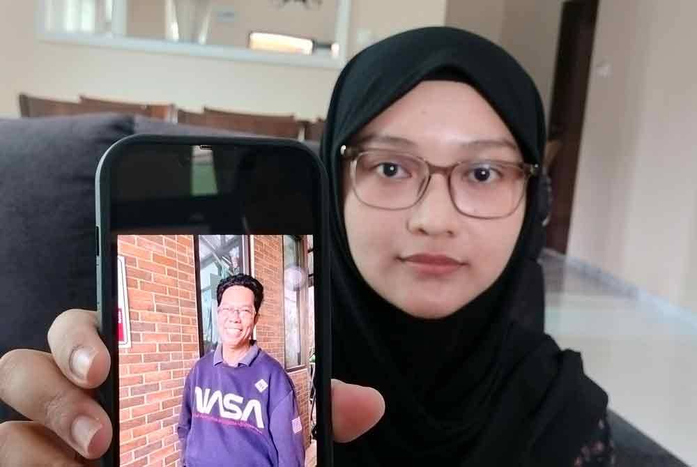 Suraiya Izzaty Sabari, 29, the eldest daughter of Sabari Baharom, 62, shows a photo of her father.