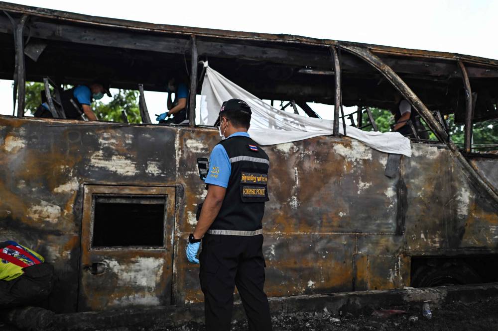 A forensic police officer takes photographs as he inspects a burnt-out bus that was carrying students and teachers on the outskirts. Photo by Manan Vatsyayana/AFP