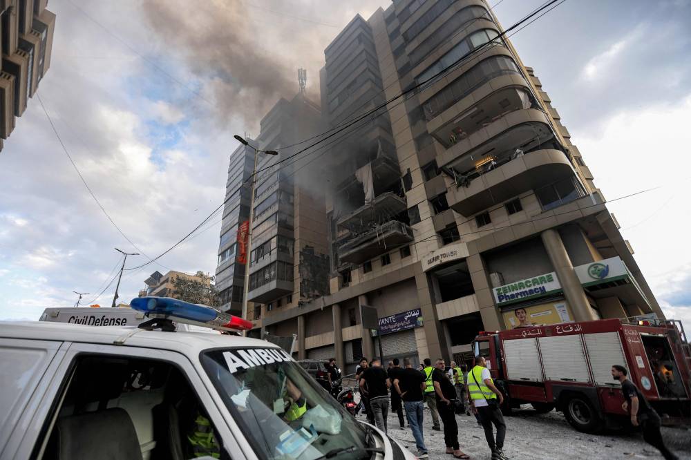 Lebanese civil defence and civilians stand at the scene of an Israeli airstrike that targeted an apartment building in south Beirut Jnah neighbourhood, on October 1, 2024. Lebanon's state-run National News Agency said Israeli strikes hit two areas of south Beirut on October 1 in the latest raids targeting Lebanese militant group Hezbollah. (Photo by AFP)