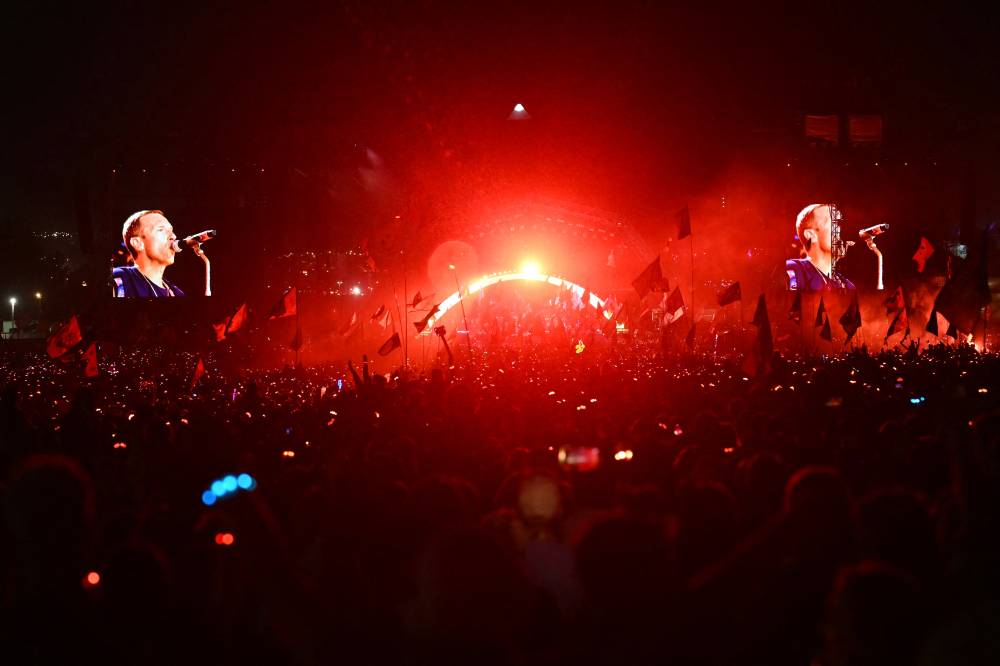A view from the crowd as Coldplay perform on the Pyramid Stage on the fourth day of the Glastonbury festival at Worthy Farm in the village of Pilton in Somerset, southwest England, on June 29, 2024. - (Photo by OLI SCARFF / AFP)