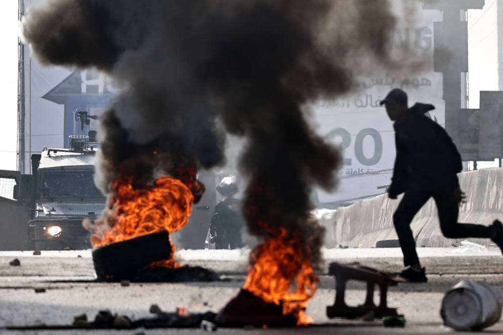 A Palestinian man runs as Israeli forces deploy during a military raid in Kafr Aqab east of Ramallah in the occupied West Bank today. Photo by Zain Jaafar/AFP