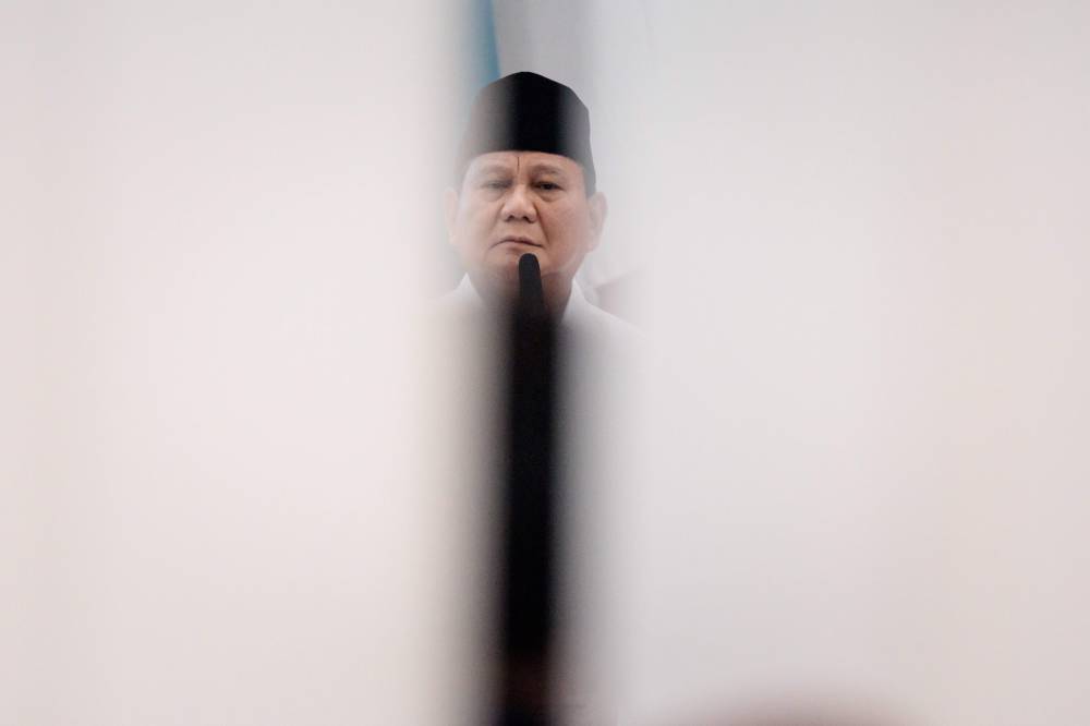 Indonesia's President-elect Prabowo Subianto is seen through a gap in the door during the plenary meeting of general election commission (KPU) announcing the 2024 presidential election in Jakarta on April 24, 2024. - Photo by AFP