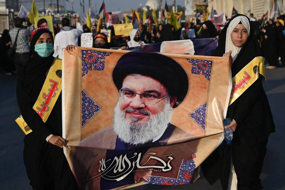 Shiite Muslim women holding a poster of Hassan Nasrallah. (Photo by AFP)