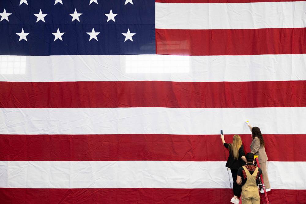 Advance staff for the Harris-Walz campaign steam wrinkles out of the US national flag beingused as a backdrop for former US President Barack Obama as he campaigns for US Vice President and Democratic presidential candidate Kamala Harris in Pittsburgh, Pennsylvania, on October 10, 2024. (Photo by RYAN COLLERD / AFP)