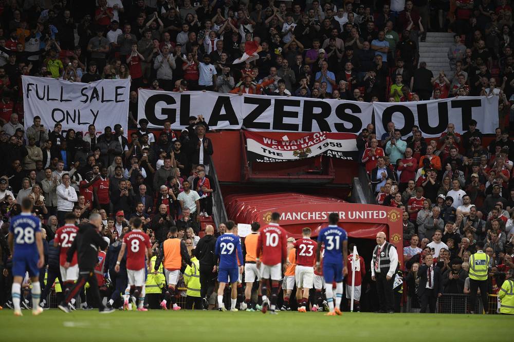 Manchester United fans display banners with messages of protest against their owners as players leave the pitch at half-time in the English Premier League football match between Manchester United and Chelsea at Old Trafford in Manchester, north west England, on May 25, 2023. (Photo by AFP)

