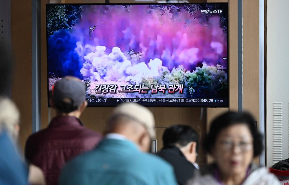 People watch a television screen showing a news broadcast with footage of an explosion on a road connecting North and South Korea on October 15, 2024, at a train station in Seoul on October 16, 2024. - Photo by AFP