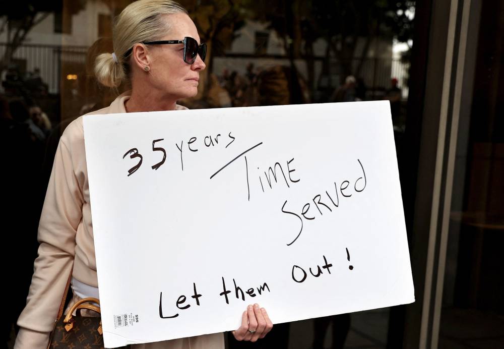 A supporter holds a sign at a press conference with Menendez family members outside the Criminal Courts Building on October 16, 2024 in Los Angeles, California. Members of the Menendez family held the news conference to call for the release of brothers Lyle and Erik Menendez from prison nearly thirty years after their conviction in 1996 for killing their parents in Beverly Hills. The district attorney’s office is looking at new evidence which supports the brothers’ claim they were sexually abused by their father. - Photo by AFP