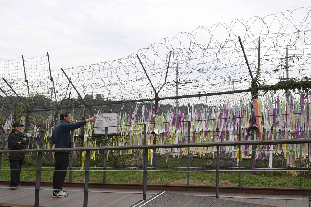 Visitors walk past a military fence at the Imjingak peace park near the Demilitarized Zone (DMZ) dividing the two Koreas in Paju on October 14, 2024. South Korea's military said on October 14 it was "fully ready" to respond after North Korea ordered troops on the border to prepare to fire in an escalating dispute over drone flights to Pyongyang. (Photo by JUNG YEON-JE / AFP)