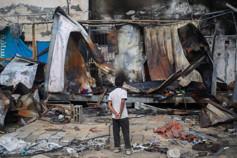 A Palestinian boy looks at destroyed shelters at the site of an Israeli airstrike which hit tents for displaced people two days earlier in the courtyard of Al-Aqsa Martyrs Hospital in Deir al-Balah in the central Gaza Strip. Photo by Eyad Baba/AFP