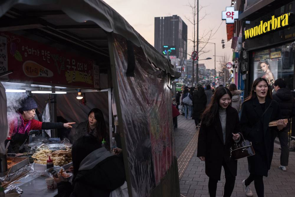 This photo taken on Feb 7, 2017 shows people walking in the Sinchon area of Seoul. - (Photo by ED JONES / AFP)