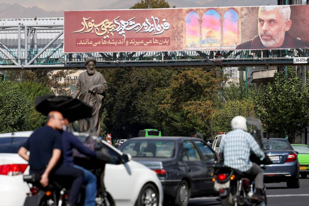 People drive past a banner bearing a portrait of Hamas' slain leader Yahya Sinwar on a highway in Tehran, on October 19, 2024. Iran's supreme leader Ayatollah Ali Khamenei said on October 19 that Hamas was alive and will survive despite the death of its leader Yahya Sinwar in an Israeli military operation in Gaza. (Photo by AFP)
