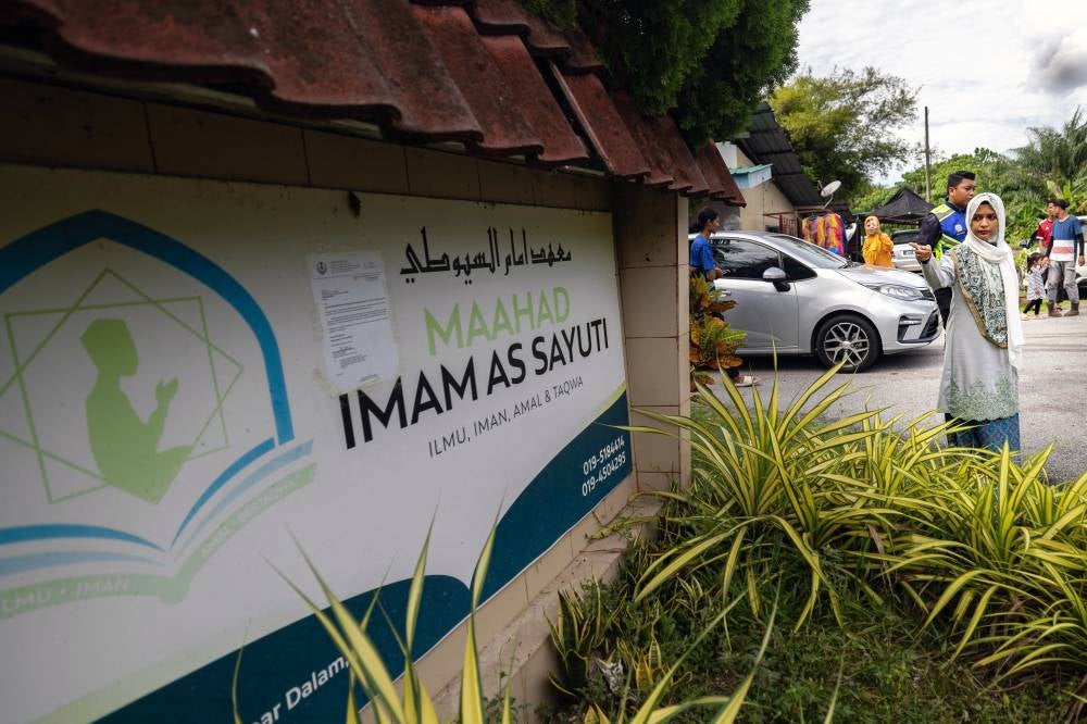 Daughter of former Al-Arqam leader Ashaari Muhammad, Ummu Atiyah, 41, pointing to a GISBH charity home in Batu Hampar. - Photo by Bernama