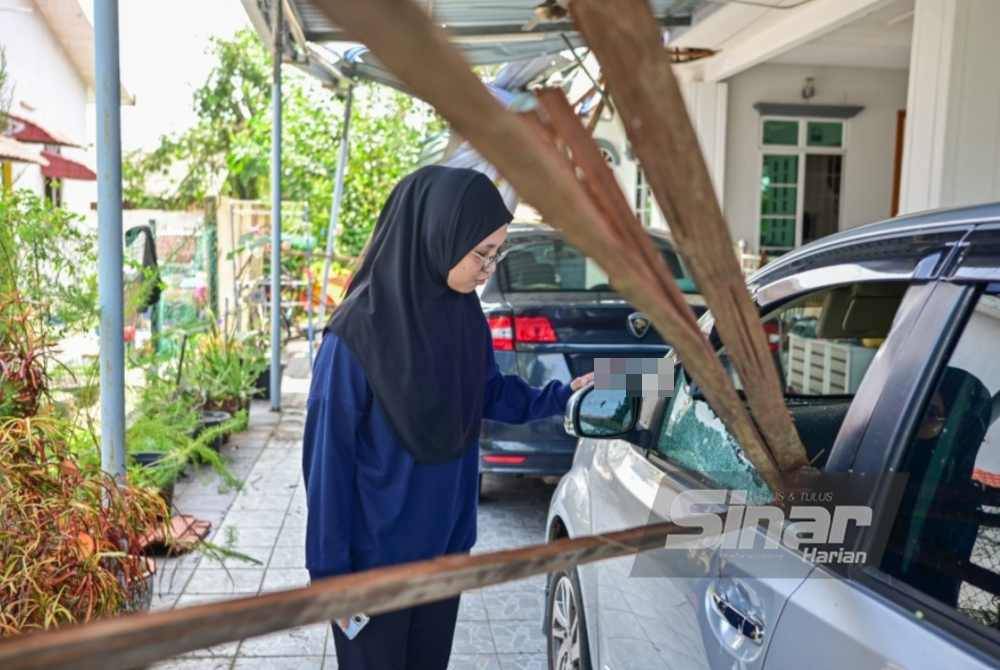 One of Zawawi's daughters inspects the shattered car window, broken by flying debris.