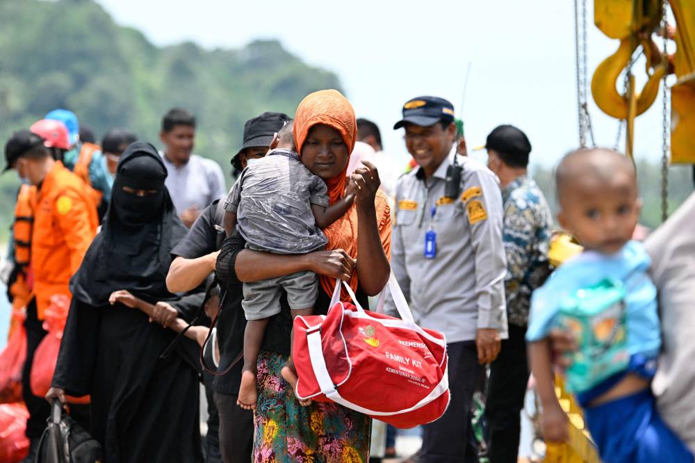 Rohingya refugees walk after being rescued from a boat after a week anchored ashore off the coast of Labuhan Haji in Southern Aceh province. Photo by Chaideer Mahyuddin/AFP