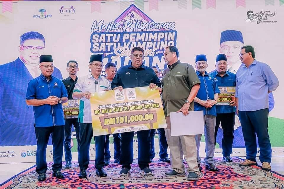 Ab Rauf presents a mock cheque to a representative of the Village Development and Security Committee (JPKK) of Kampung Balik Batu during the programme.
