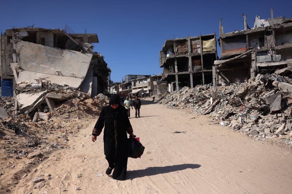 Palestinians walk past damaged buildings in Khan Yunis on the southern Gaza Strip on Oct 29, 2024, amid Israeli attacks. - (Photo by BASHAR TALEB / AFP)