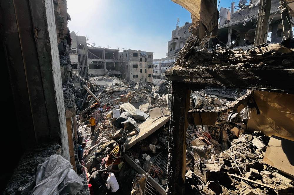 Palestinians search throught the rubble of a building after an Israeli strike in Beit Lahia, in the northern Gaza Strip. Photo by AFP