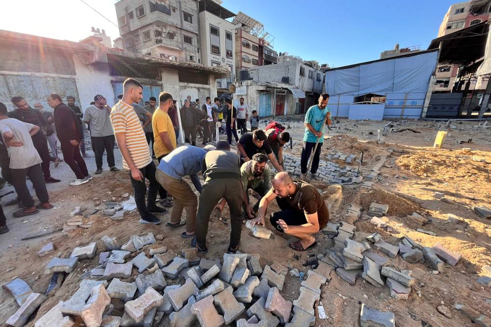 Men bury victims of Israeli air strikes at a makeshift cemetary in Beit Lahia in the northern Gaza Strip. Photo by AFP