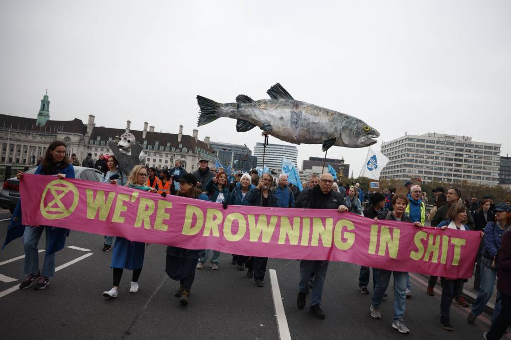 People march behind an Extinction Rebellion banner as they take part in a "March for Clean Water" in London on November 3, 2024, calling for the government to "stop the poisoning of Britain's waters". (Photo by BENJAMIN CREMEL / AFP)