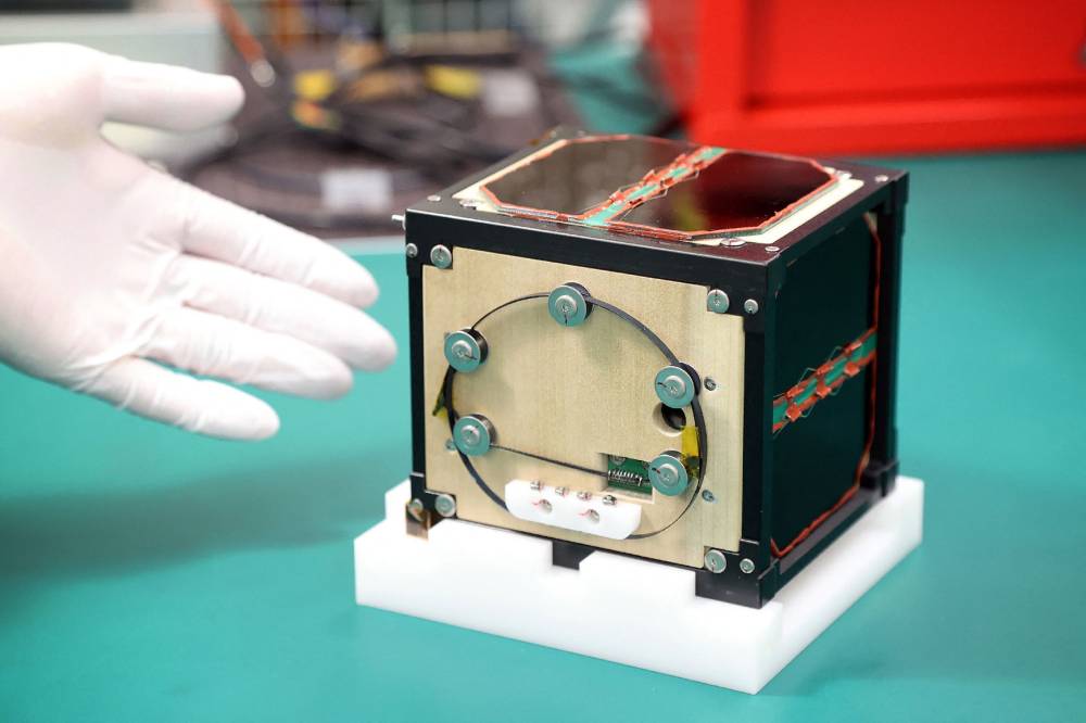 This file photo taken on May 28, 2024 shows the world's first satellite made from wood, named LignoSat, developed by scientists at Kyoto University and logging company Sumitomo Forestry, during a press conference in Kyoto. The world's first wooden satellite has blasted off on a SpaceX rocket, its Japanese developers said on November 5, 2024, part of an resupply mission to the International Space Station. (Photo by AFP