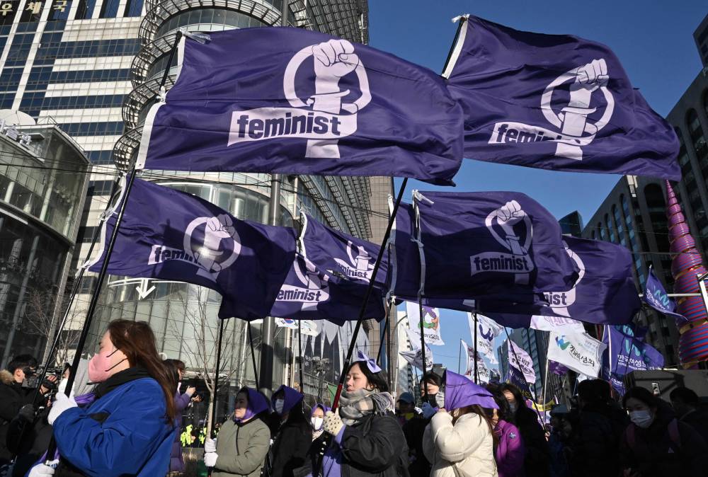 South Korean women carry flags reading "Feminist" as they march during a rally to mark International Women's Day in downtown Seoul. Photo by Jung Yeon-Je/ AFP