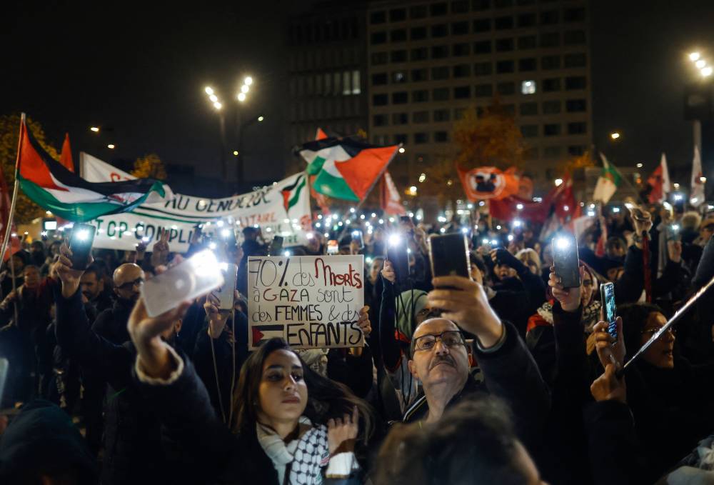 Protestors hold smartphones with flashes actived as they take part in a demonstration against the holding of the UEFA Nations League Group A2 football match between France and Israel prior to the start of the game, in Aubervilliers, in the northern outskirts of Paris, on November 14, 2024. The French team will host Israel in a very tense atmosphere on November 14, 2024, at the Stade de France, where an exceptional security presence has been put in place in the midst of the conflict in the Middle East, with tensions exacerbated by last week's violence on the sidelines of a Maccabi Tel-Aviv match in Amsterdam. (Photo by Ian LANGSDON / AFP)